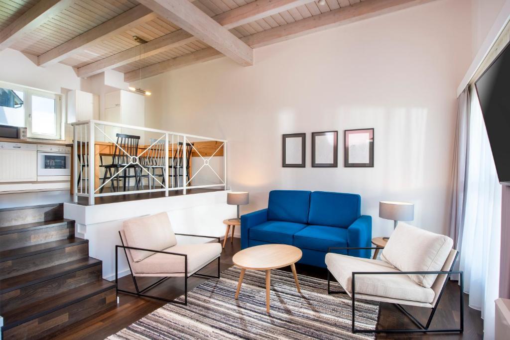 a living room with a blue couch and chairs at Precise Resort Marina Wolfsbruch - Familienapartments in Rheinsberg