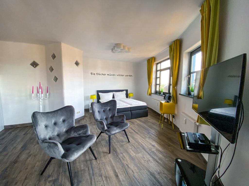 ein Schlafzimmer mit einem Bett, 2 Stühlen und einem TV in der Unterkunft apartHOTEL Magdeburg in Magdeburg