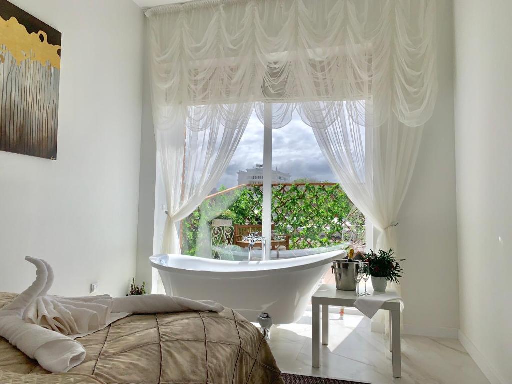 um quarto com uma grande janela com uma banheira e uma cama em 7 Boutique Hotel em Ustʼ-Kamenogorsk