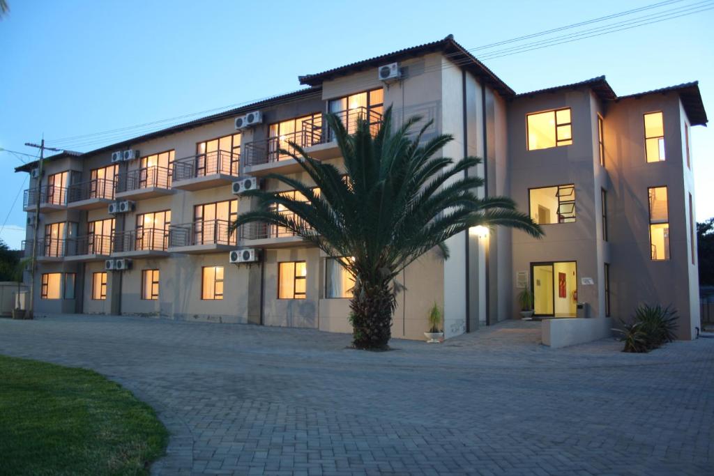 ein großes Gebäude mit einer Palme davor in der Unterkunft Oasis Hotel in Mokopane