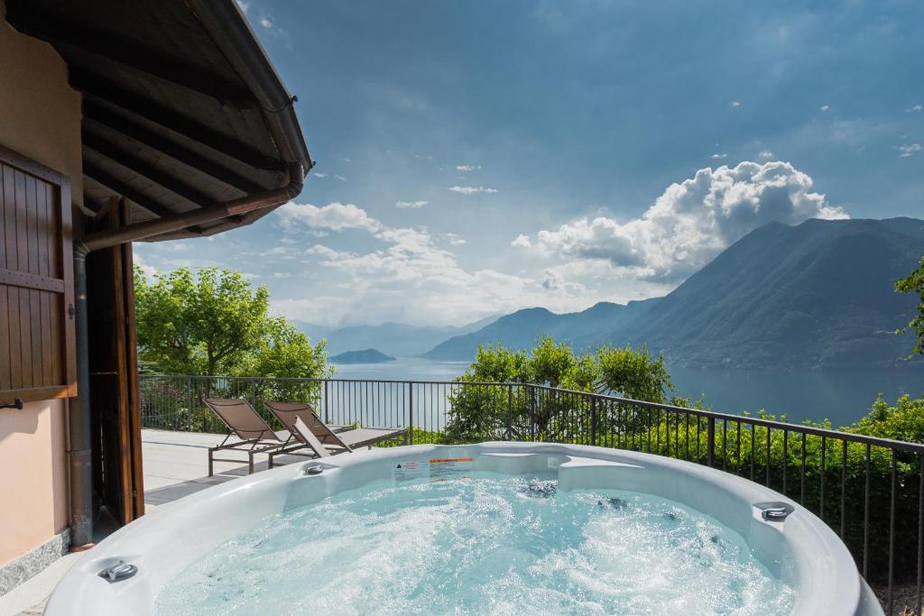 uma banheira de hidromassagem numa varanda com vista para as montanhas em Villa Castello with jacuzzi & priceless view by Rent All Como em Argegno