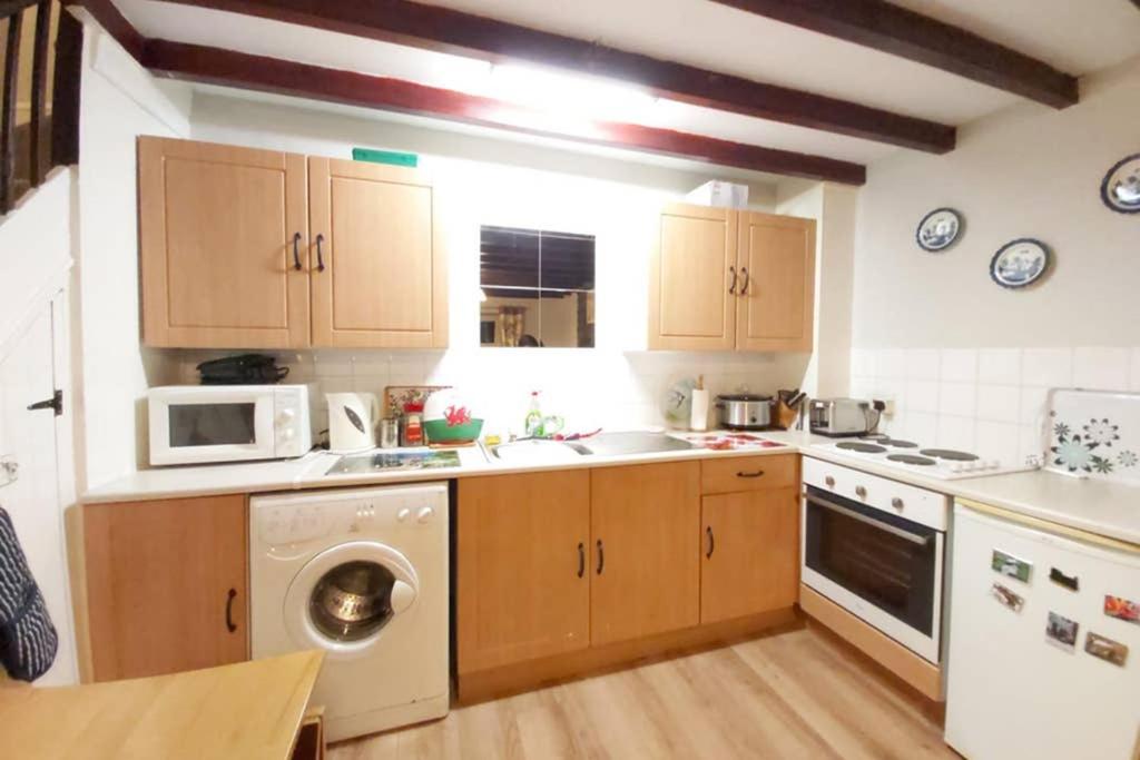 a kitchen with a washing machine and a microwave at Self Catering Cottage in Talsarnau