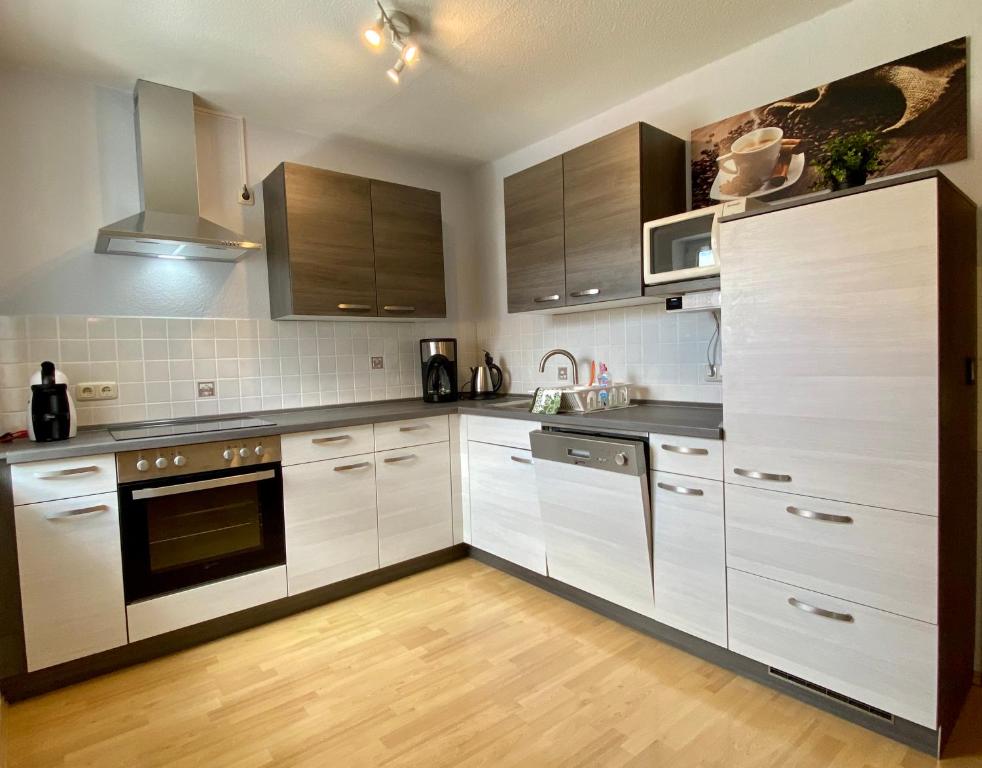 una cucina con armadietti bianchi ed elettrodomestici in acciaio inossidabile di FeWo Riedel a Weida
