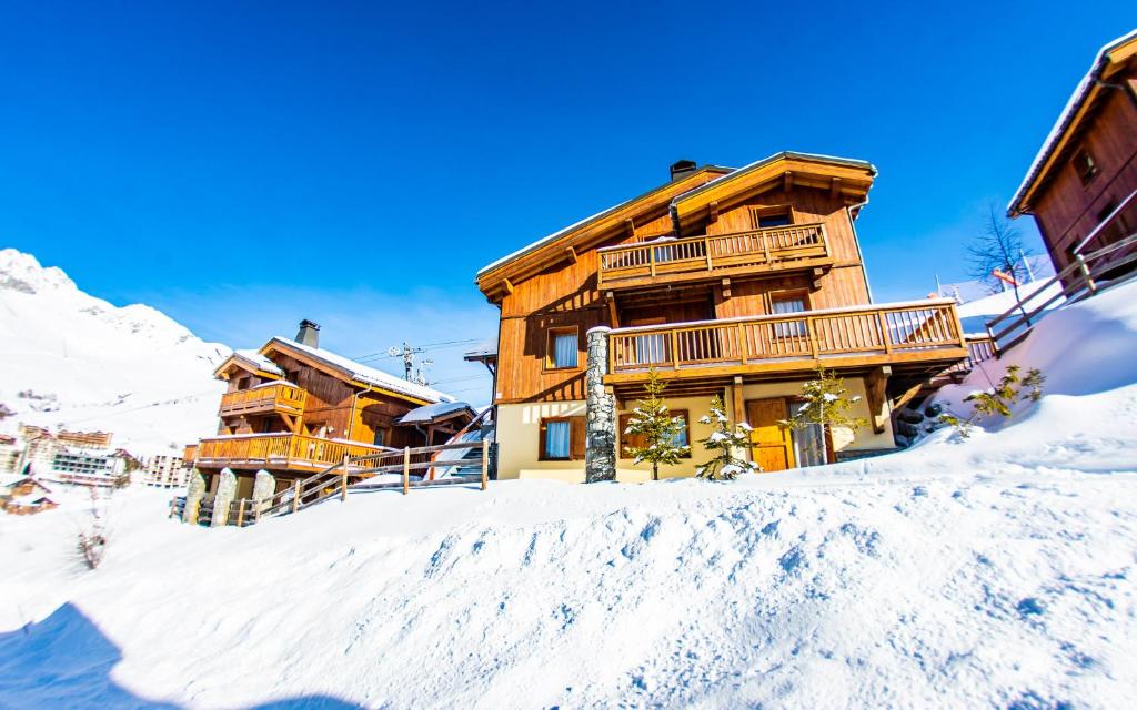 ein Holzhaus im Schnee mit einem Berg in der Unterkunft Parc Madeleine - APARTMENTS in Saint-François-Longchamp