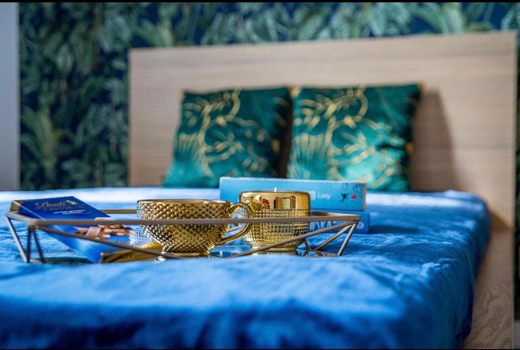 a blue bed with two serving dishes on it at Apartamenty Centrum in Bydgoszcz