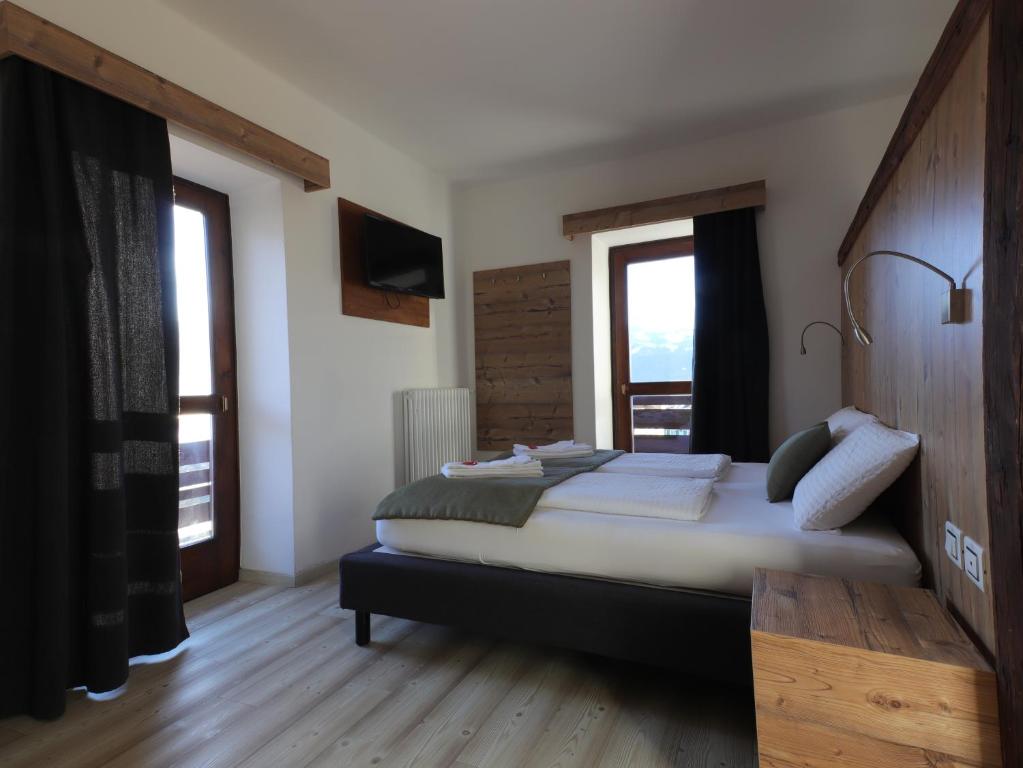 a bedroom with a large bed in a room with windows at Hotel Alla Rocca in Varena