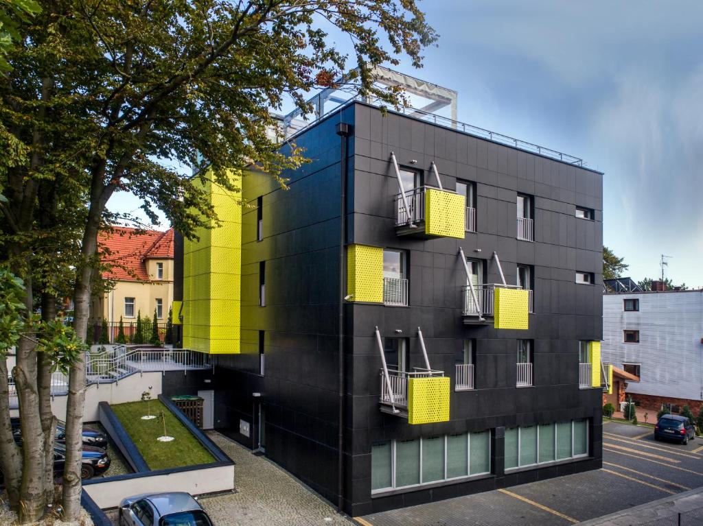 un bâtiment noir avec des fenêtres jaunes et un parking dans l'établissement Villa Buki Pokoje & SPA, à Jastrzębia Góra