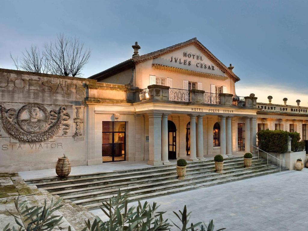 Un grand bâtiment avec des escaliers se trouve juste devant. dans l'établissement Hôtel & Spa Jules César Arles - MGallery Hotel Collection, à Arles