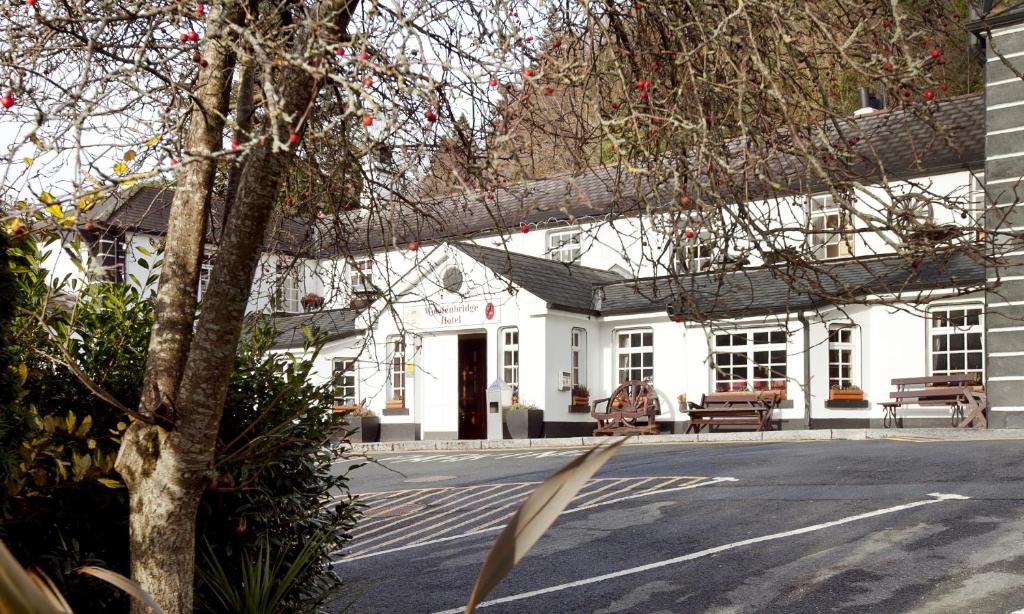 a white building with a tree in front of it at Woodenbridge Hotel in Arklow