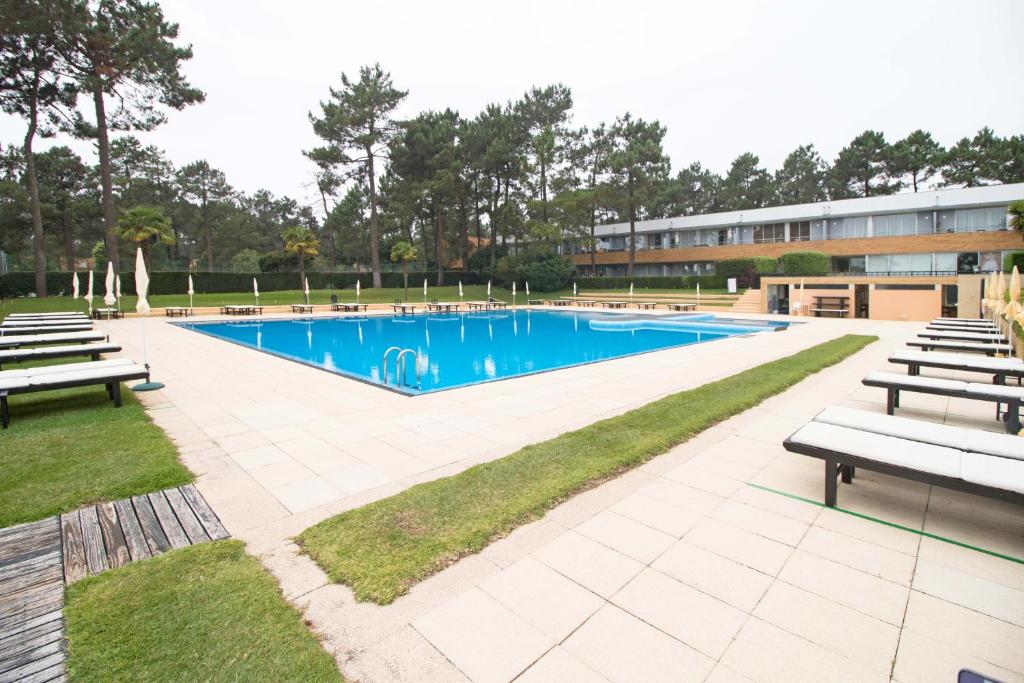 ein großer Pool mit Bänken und ein Gebäude in der Unterkunft CLEYMALIA - Quinta da Barca in Esposende