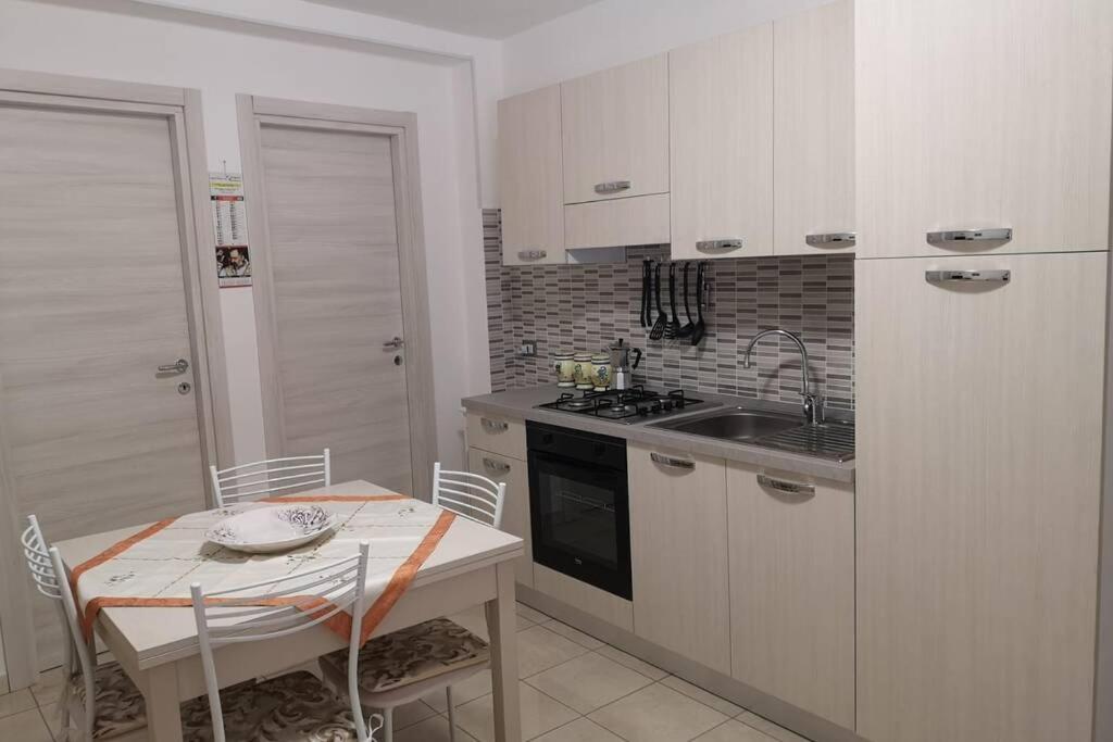 eine Küche mit weißen Schränken, einem Tisch und einem Waschbecken in der Unterkunft Lalù in Chiaramonte Gulfi