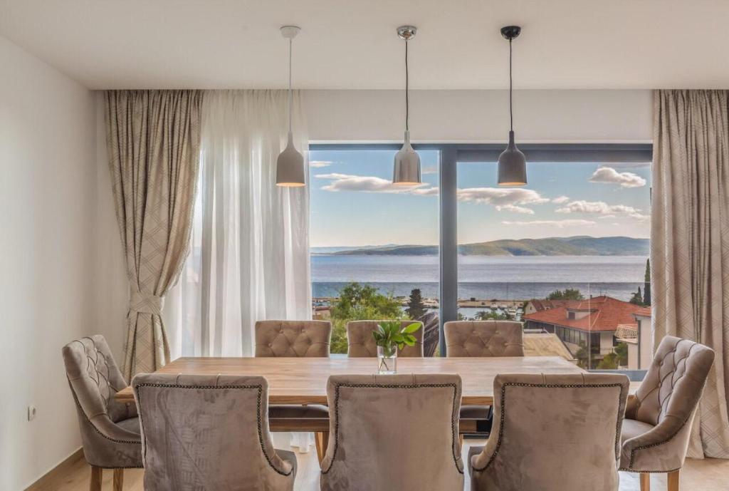 une salle à manger avec une table, des chaises et une grande fenêtre dans l'établissement Apartmani Arapovic, à Baška Voda