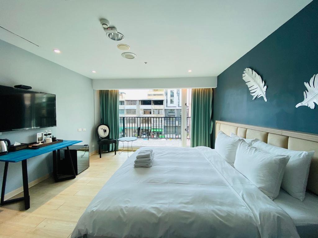 1 dormitorio con 1 cama grande y pared azul en Taichung EnrichLife Hotel en Taichung