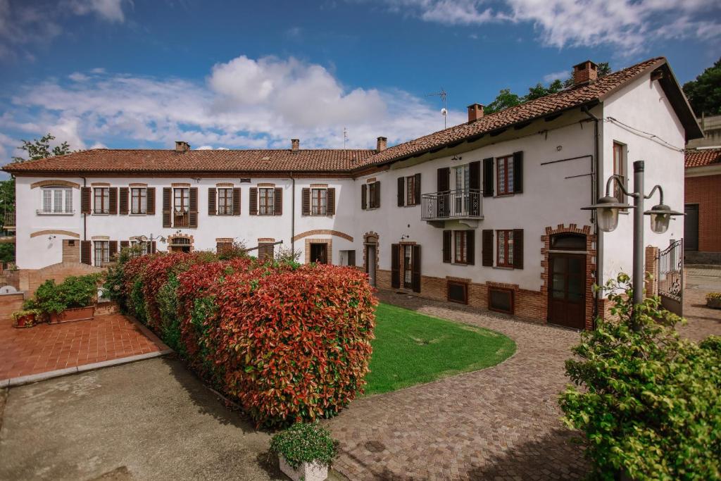 una gran casa blanca con un seto delante de ella en Il Pozzo Fiorito, en Cossombrato