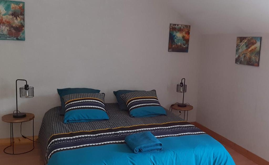 a bedroom with a bed with blue sheets and pillows at Le gîte de l'atelier in Lailly-en-Val