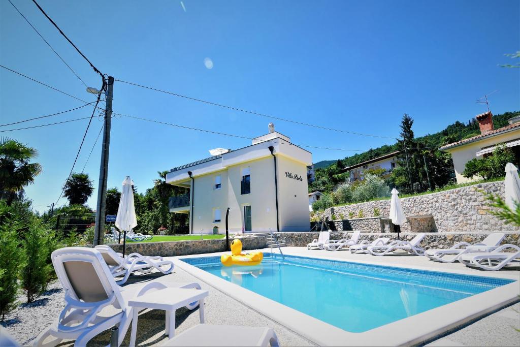 uma villa com uma piscina e espreguiçadeiras em Villa Perla with swimming pool, Lovran - Opatija em Lovran