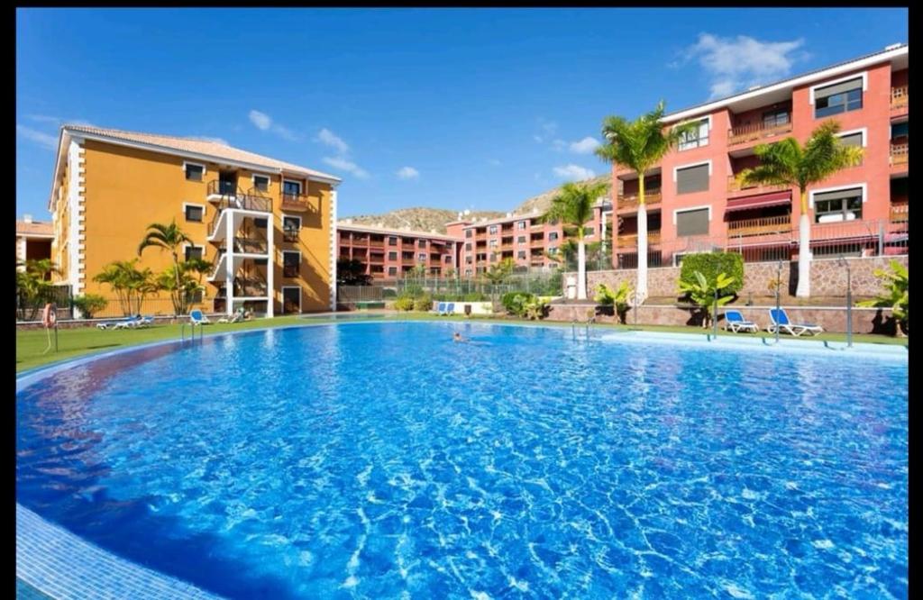 una gran piscina frente a algunos edificios en Apartamento de lujo en Residencial El Mocan, en Palm-mar