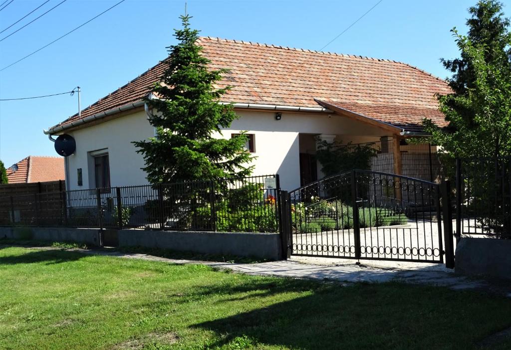 a white house with a fence and a tree at Melody Huis in Poroszló