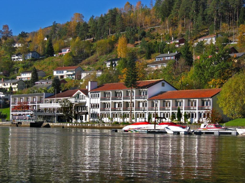 un groupe de bâtiments sur la rive d'un lac dans l'établissement Strand Fjordhotel, à Ulvik