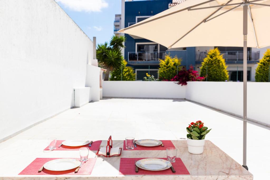 - une table pour le dîner sur une terrasse avec un parasol dans l'établissement Ericeira Central Apartment, à Ericeira