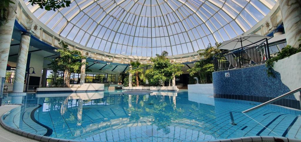 een groot zwembad in een gebouw met een glazen plafond bij Vital Hotel Rhein Main Therme Wellness Resort & SPA in Hofheim am Taunus
