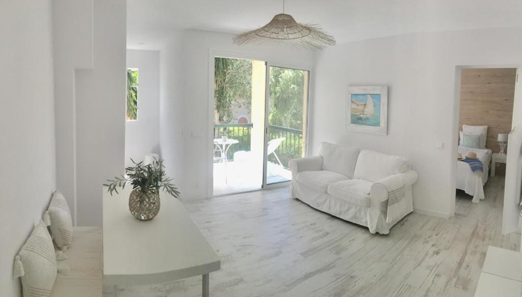 ein weißes Wohnzimmer mit einem Sofa und einem Tisch in der Unterkunft Apartment BEACH & RELAX in Port de Pollença