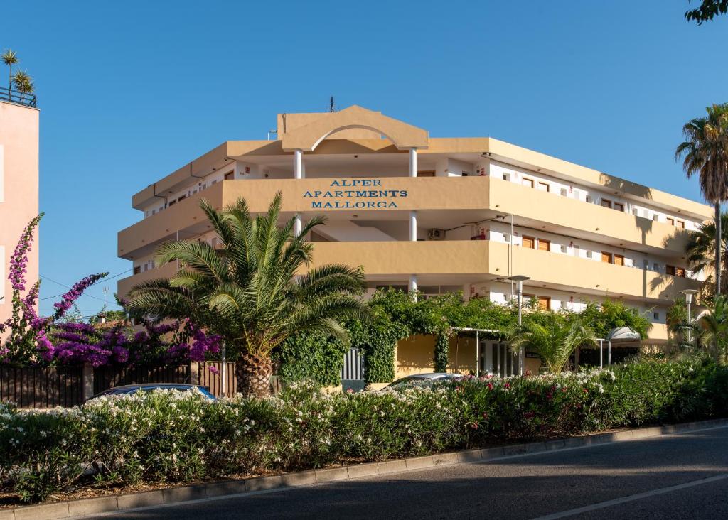 a building with palm trees in front of a street at Alper Apartments Mallorca in Palmanova