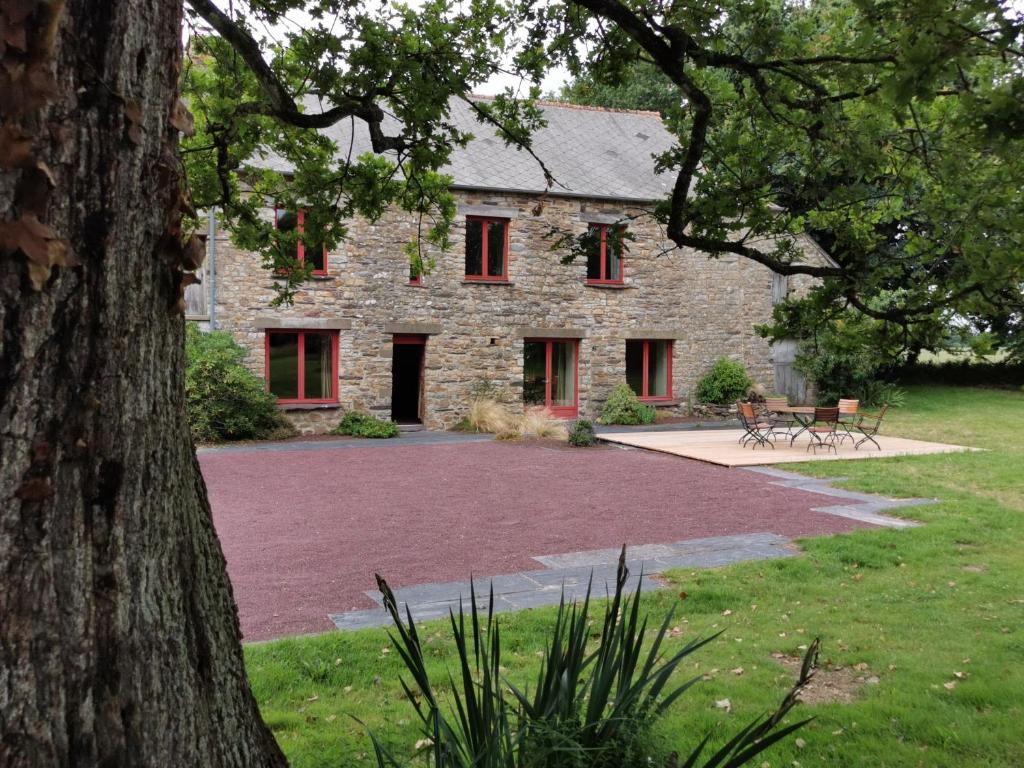 una casa de piedra con ventanas rojas y un árbol en Ar Merglet - Grande longère authentique en Brocéliande en Maxent