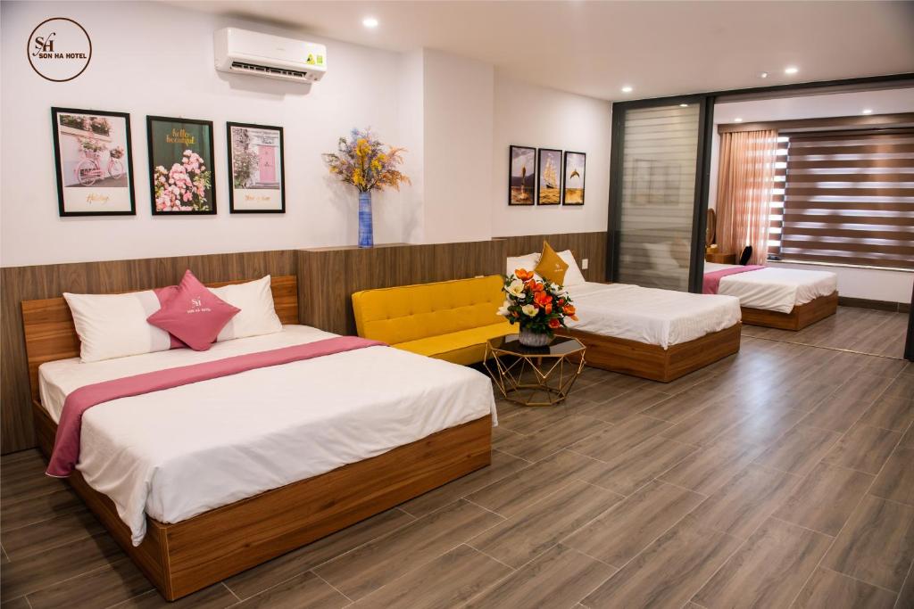 a bedroom with two beds and a yellow couch at Sơn Hà Hotel in Quy Nhon