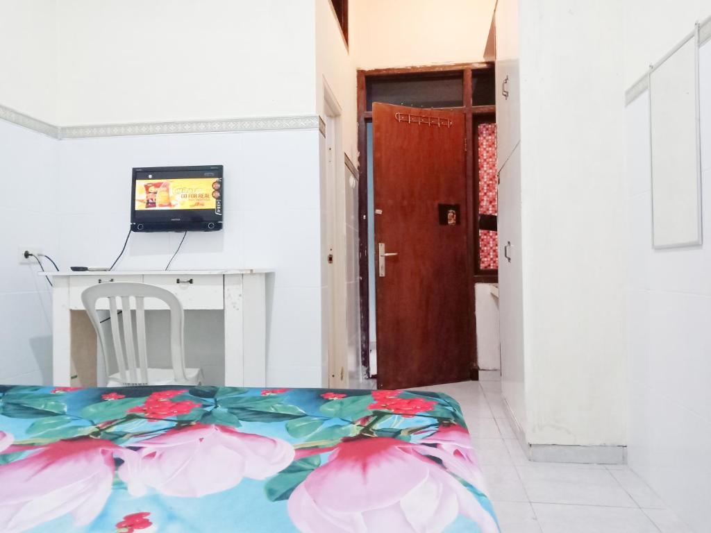 een kamer met een bed, een bureau en een deur bij D'Kost Ketintang in Surabaya