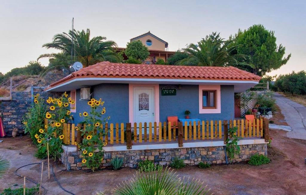 une petite maison bleue avec une clôture et des tournesols dans l'établissement Pelegrines V., à Palekastro