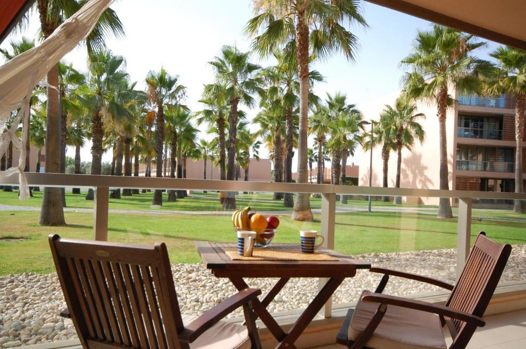 a table and chairs on a patio with palm trees at Apartamentos Herdade dos Salgados in Albufeira