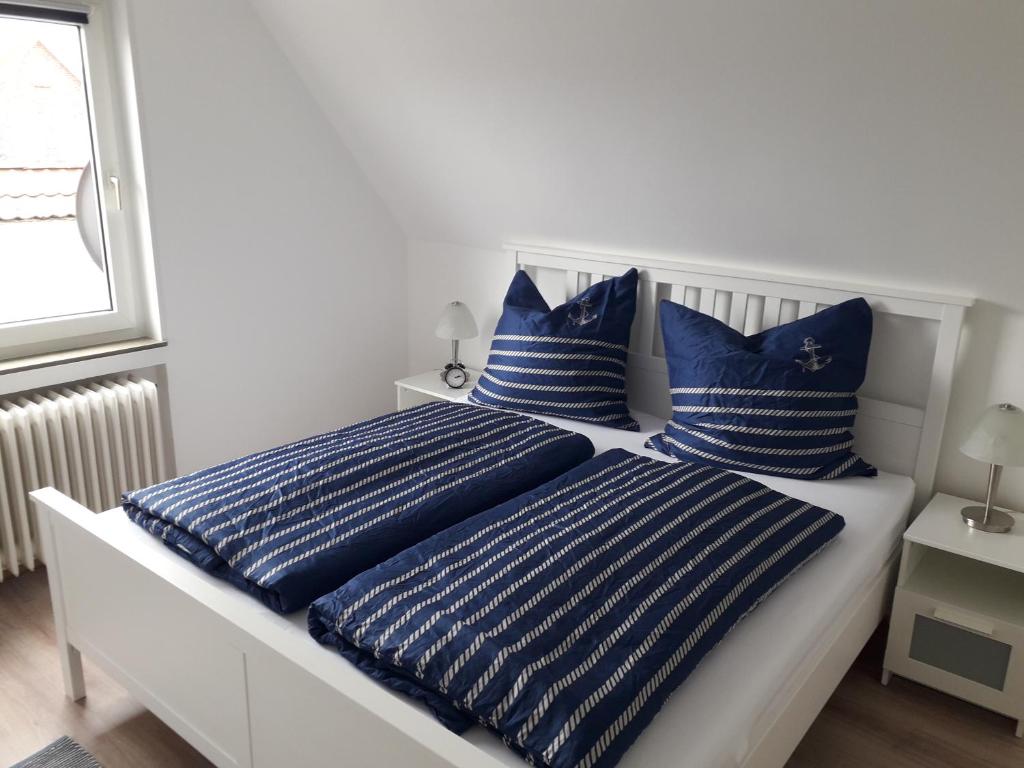 1 dormitorio con 2 camas y almohadas azules y blancas en Möwennest, en Neuharlingersiel