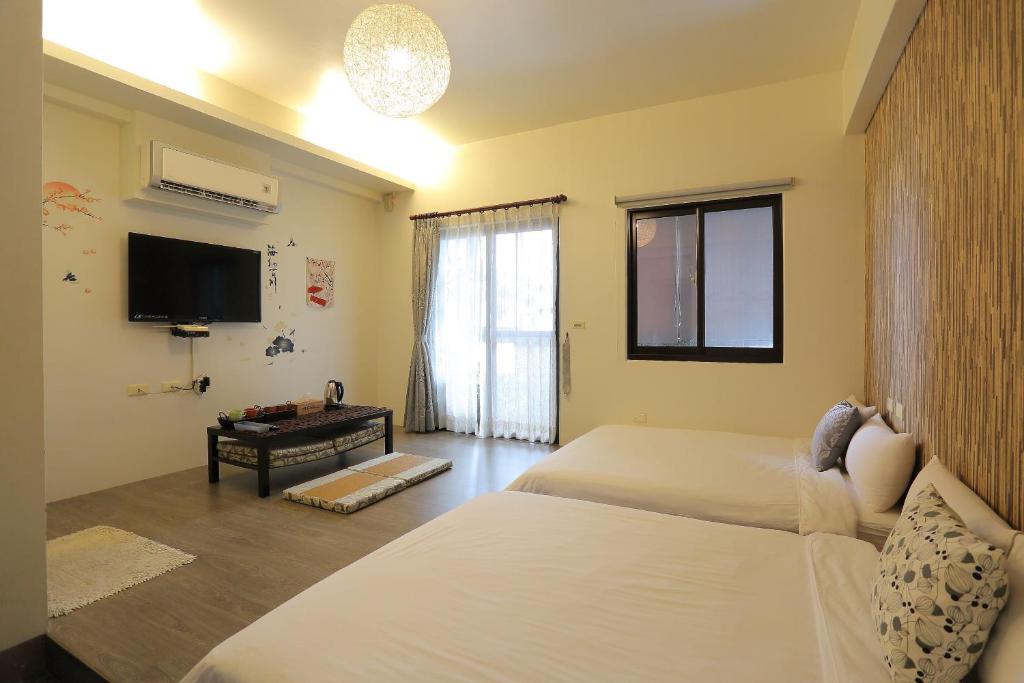 a bedroom with two beds and a flat screen tv at Redbean Guesthouse in Wujie