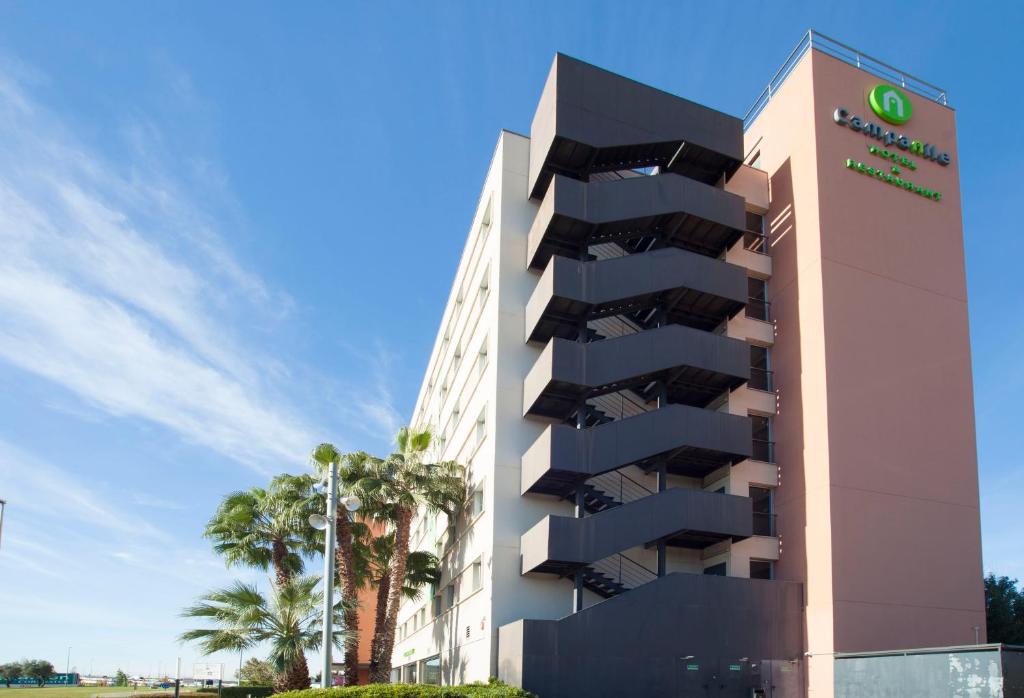 a building with a hotel sign next to palm trees at Campanile Barcelona Sud - Cornella in Cornellà de Llobregat