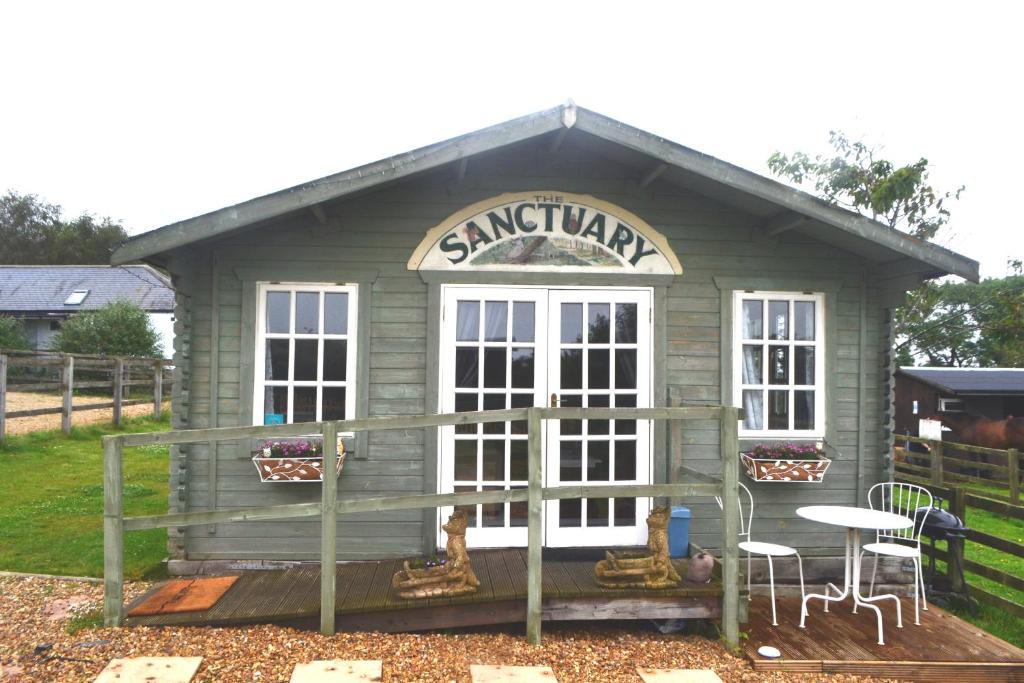 ein kleiner Schuppen mit einem Tisch und Stühlen in der Unterkunft Peaceful Log Cabin next to Horse Field in Morpeth