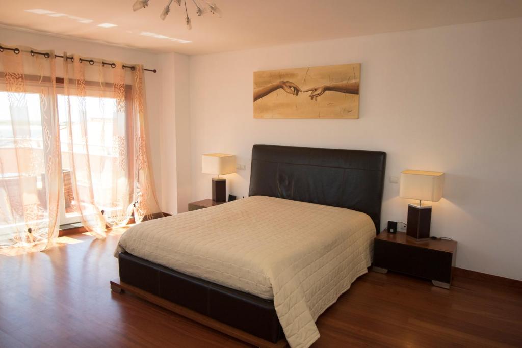 a bedroom with a large bed and two lamps at RIVERZENHOUSE in Esposende