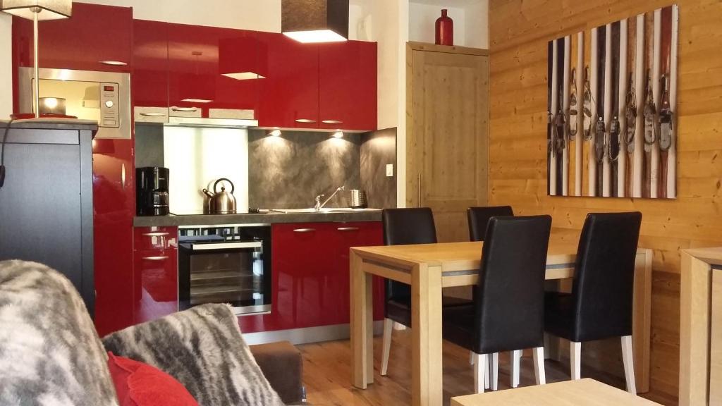 a kitchen with red cabinets and a wooden table at T2 cabine vue montagne Valnéa Peyragudes in Germ