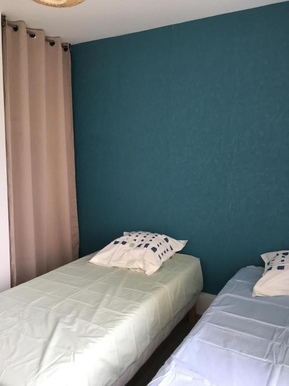 two beds in a room with a blue wall at La Tanatte de wimereux sur la côte d opale in Wimereux