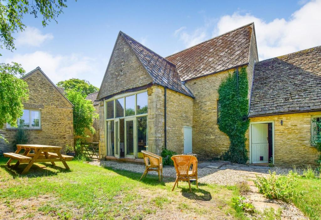 ein Cottage mit einem Picknicktisch und Stühlen im Hof in der Unterkunft Butts Farm in Cirencester