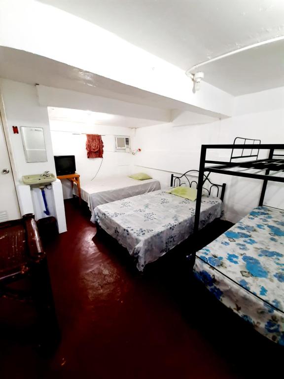 a room with three beds and a tv in it at Antipolo Budget Hostel,Family Rooms in Antipolo