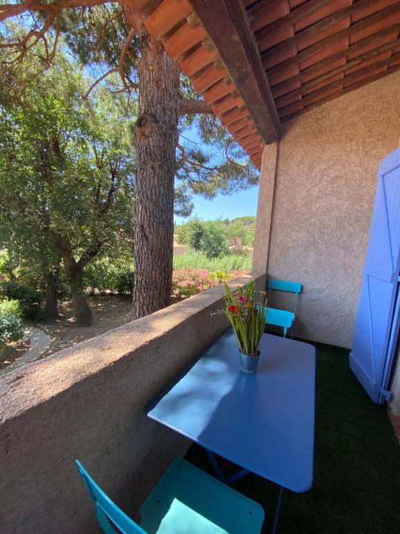 een blauwe tafel en stoelen op een veranda met een boom bij Appartement Les grands pins in Les Issambres