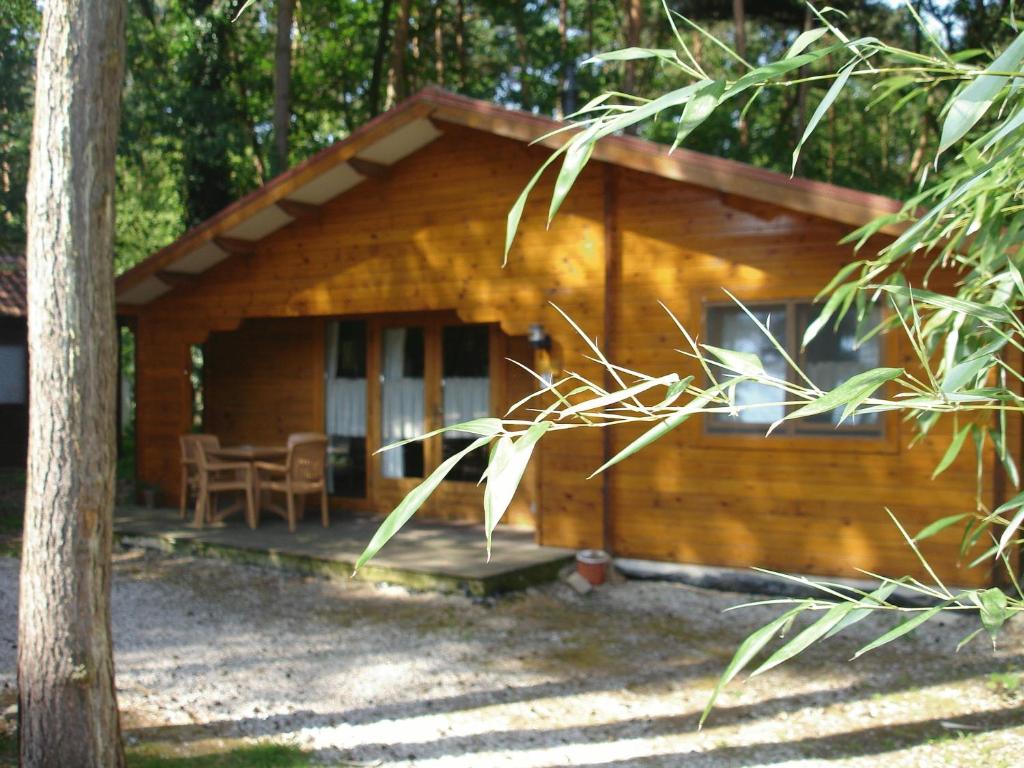 Blockhaus mit einer Veranda und einem Tisch in der Unterkunft Motel- Bungalow-& Chaletpark de Brenkberg in Schinveld