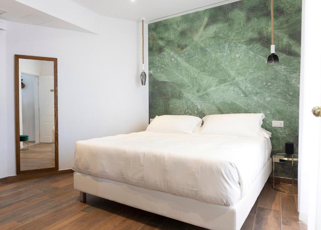 1 dormitorio con cama blanca y pared verde en Il Caruggio Rooms&Breakfast, en Varazze