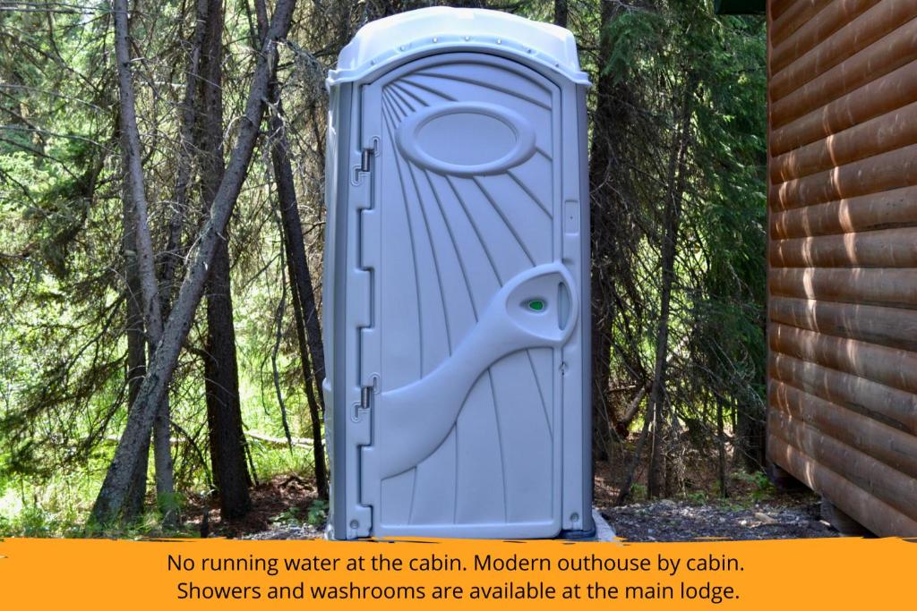 a outhouse with a door in the woods at Schott's Lake Conference & Resort in Sundre