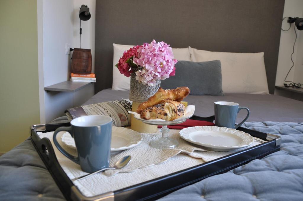 a tray of food on a bed with a table with cups at The flat via roma 45 in Bassano del Grappa