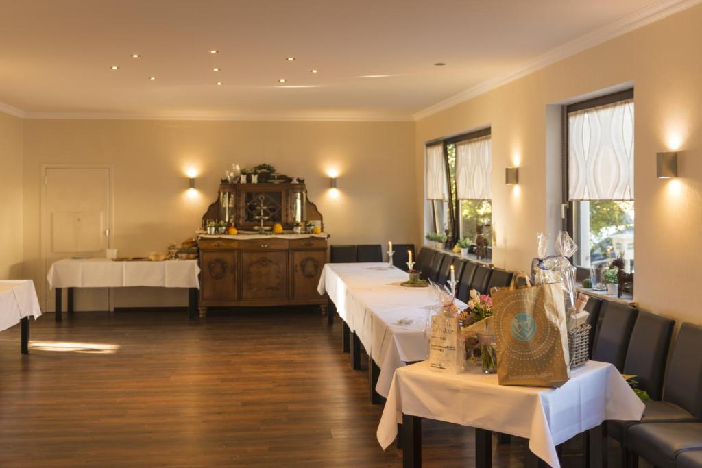ein Restaurant mit weißen Tischen, Stühlen und Fenstern in der Unterkunft Hotel Restaurant Häsfeld in Überherrn