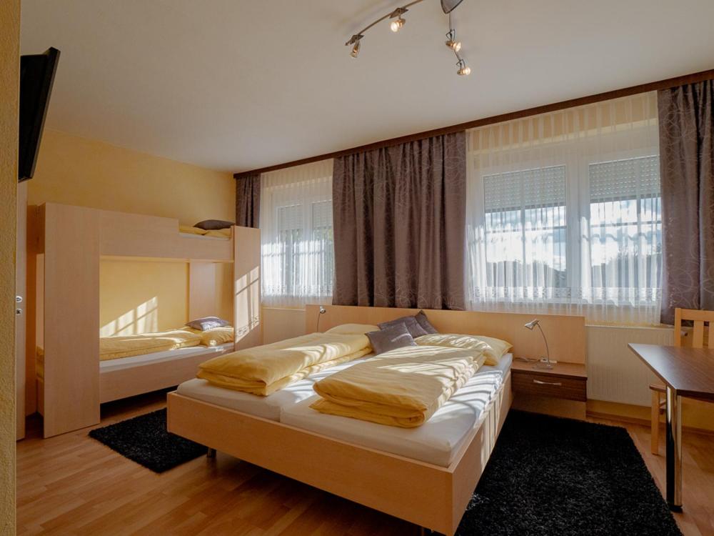 1 dormitorio con 2 camas, mesa y ventanas en Gasthof Familie Hutter, en Rattersdorf