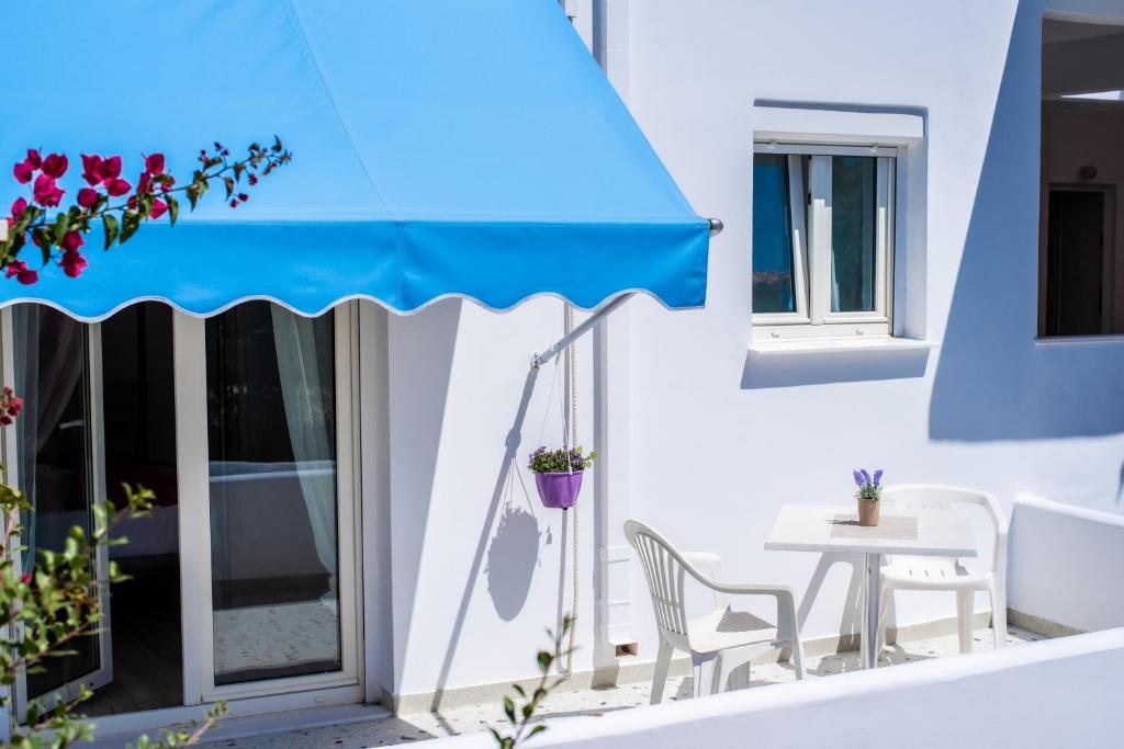a patio with a blue umbrella and a table and chairs at Nemesis Studios in Aegina Town