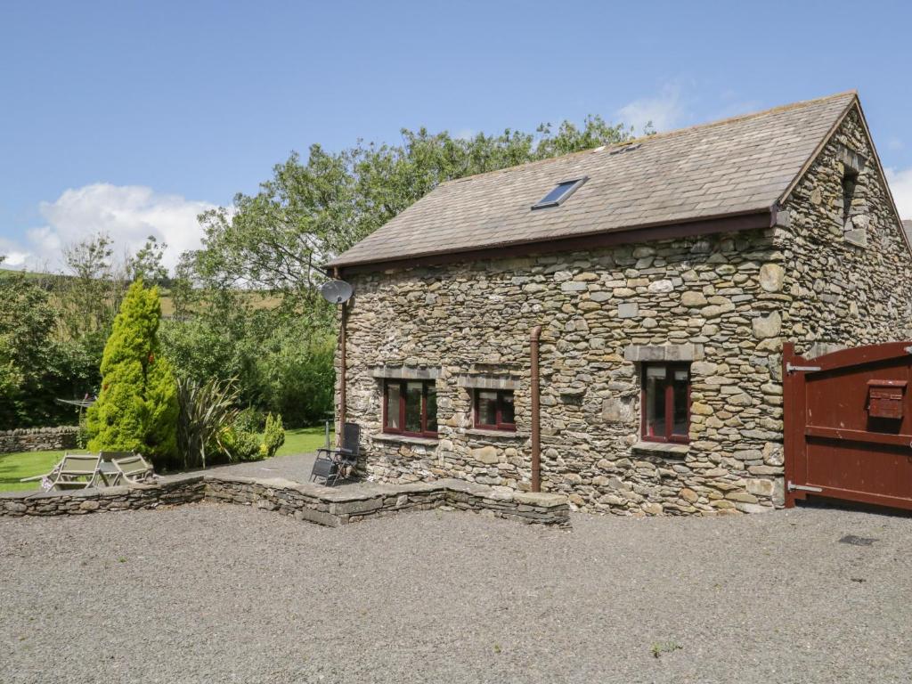 a stone house with a garage in a driveway at Woodside Barn in Ulverston
